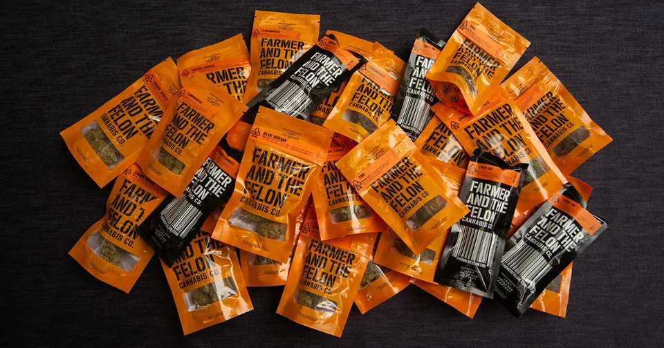 Pile of orange and black condiment packets scattered on a dark surface.